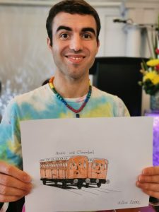 Alex holding his drawing of two anthropomorphized trains with faces named Annie and Clarabel