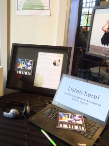 A framed display of Colin Darge's CD The Gift and a laptop which displays the message, "Listen here! Use the headphones to listen to Colin's music!"
