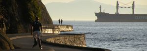 A man faces away from the camera, rollerblading on the Stanley Park Seawall.