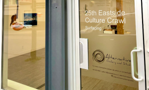 The glass front door of Alternatives Gallery with a sticker that reads "25th Eastside Culture Crawl: Surfacing"